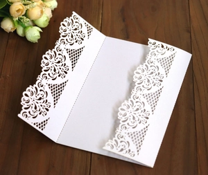 Macro shot of laser-cut lace wedding invitation cover in white pearl paper