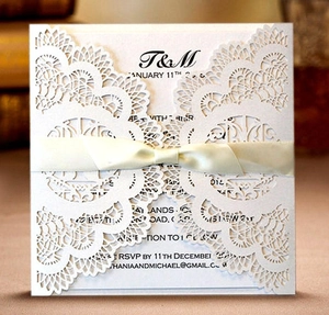 Elegant gold laser cut lace wedding invitation with a cream ribbon bow and inner card