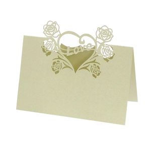 Detail of laser-cut heart and rose design on iridescent light green wedding place card