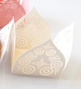 Macro view of laser-cut floral patterns on beige and pink wedding candy gift boxes