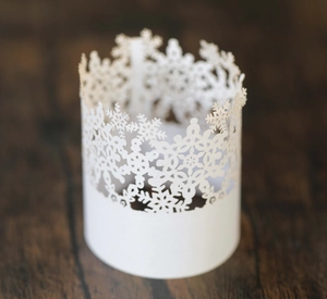 Close-up of white snowflake laser-cut paper lampshade on dark walnut wood background