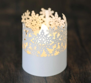 Detailed laser-cut snowflake paper lantern with warm LED glow on wooden surface