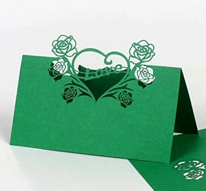 Macro shot of green laser-cut table card featuring hollow heart and rose patterns