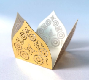 Macro view of laser-cut golden favor box featuring intricate star and circle patterns