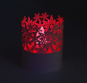 Macro shot of laser-cut snowflake pattern on black lampshade with warm red LED light