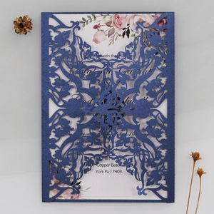 Macro view of laser-cut floral wedding invitation with rose insert on textured background