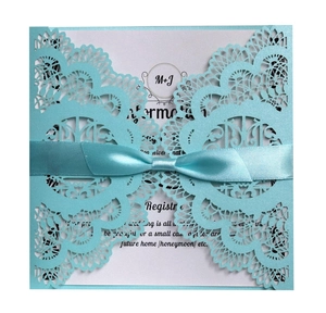 Detail of laser-cut floral wedding invitation with Tiffany blue lace and satin ribbon