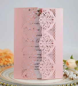 Macro detail of laser-cut rose gold wedding invitation with intricate lace floral patterns
