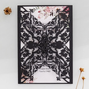 Detail of laser-cut black wedding invitation cover with elegant floral lace and inner card