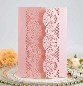 Close-up of laser cut floral patterns on a pearlescent pink wedding invitation sleeve