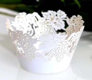 Macro view of white laser-cut cupcake wrapper featuring intricate grape vine patterns