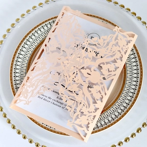 Close-up of champagne laser-cut invitation card with floral patterns on a white plate