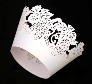Macro shot of white laser-cut cupcake wrappers with grape and leaf vine patterns