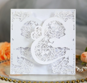 Macro detail of laser-cut wedding invitation featuring elegant white lace floral patterns