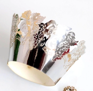 Close-up of laser-cut silver cupcake wrapper featuring detailed vine and grape patterns