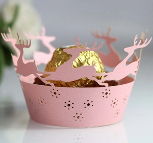 Close-up of pink laser-cut cupcake wrapper with reindeer silhouettes and golden chocolate