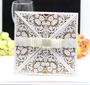 Elegant laser-cut white lace wedding invitation with ivory satin bow and kraft insert