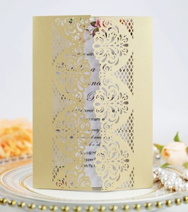 Detail of laser-cut floral wedding invitation with golden finish and elegant insert card
