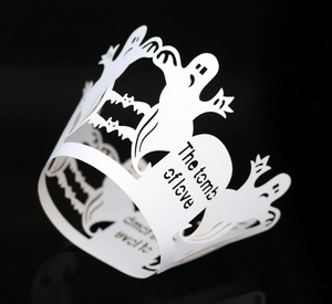 Macro detail of laser-cut white Halloween cupcake wrapper with ghost and bat patterns