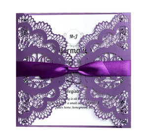 Detail of laser-cut purple lace invitation with a deep violet satin ribbon bow