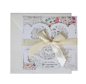 Laser cut wedding invitation with floral patterns and a cream silk ribbon bow