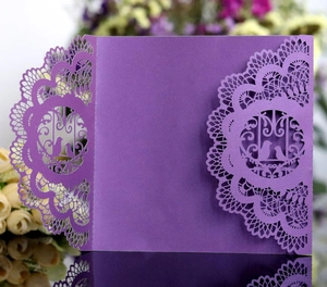 Macro detail of laser-cut wedding card featuring intricate lace edges and love birds