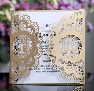 Close-up of laser-cut lace and floral patterns on a gold reflective wedding invitation