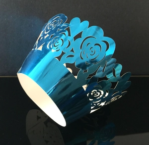 Detailed laser-cut rose pattern on metallic blue cupcake wrapper with reflective finish