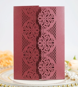 Close-up of burgundy laser-cut lace floral pattern on elegant wedding invitation cover