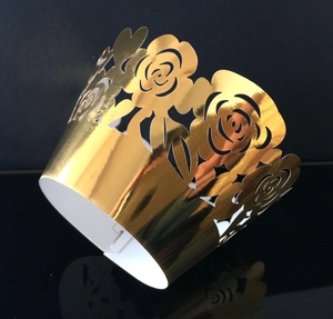 Detailed macro view of laser-cut rose floral pattern on golden cupcake wrapper décor