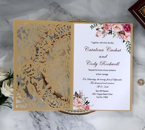 Détail du faire-part de mariage ajouré au laser avec motif floral doré et insert élégant