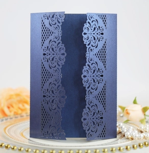 Detail of laser-cut navy blue wedding invitation with floral patterns on a white plate