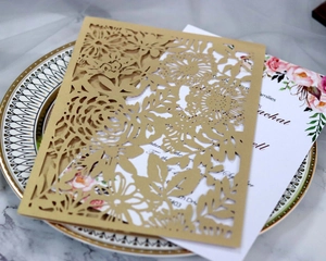 Détails de motifs de roses découpés au laser sur couverture d'invitation dorée nacrée