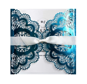 Detailed laser-cut peacock blue wedding invitation with elegant white ribbon and inner card