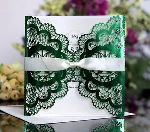 Detailed laser-cut dark green wedding invitation with elegant silk ribbon bow and flowers