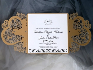 Macro view of gold laser-cut wedding invitation with intricate vine and heart patterns