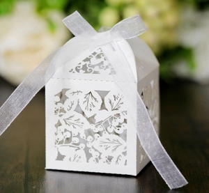 Détail boîte cadeau blanche découpée au laser avec motif feuilles et ruban élégant