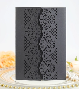Detail showing the intricate laser-cut European damascus pattern on black wedding invitation cover