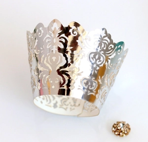 Macro detail of silver laser-cut cupcake wrapper with damascus pattern and gold rhinestone
