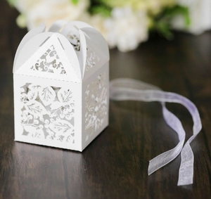 Détails de motifs de feuilles découpés au laser sur boîte à bonbons blanche et ruban lavande