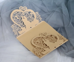 Detail of laser-cut gold wedding invitation with silhouettes of kissing couple