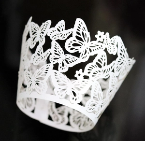 Close-up of white laser-cut butterfly cupcake wrappers with intricate hollow details