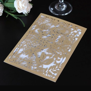Vue détaillée du faire-part de mariage doré ajouré au laser avec sa carte intérieure blanche