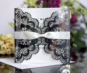 Detail of silver laser-cut wedding invitation with elegant ivory ribbon and lace patterns