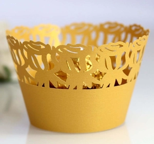 Detail of laser-cut gold cupcake wrapper featuring intricate rose floral hollow design