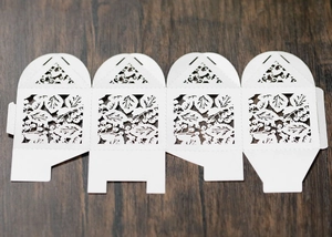 Vue à plat de la boîte cadeau blanche découpée au laser avec motifs de feuilles, dépliée