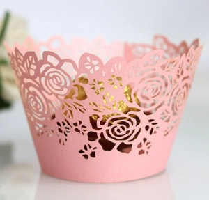 Close-up of pink laser-cut cupcake wrappers with elegant rose patterns for weddings