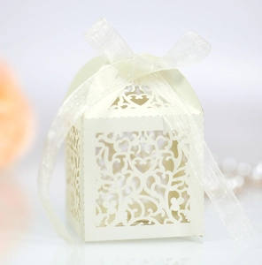 Detail of laser-cut heart pattern on cream wedding candy box with organza ribbon bow