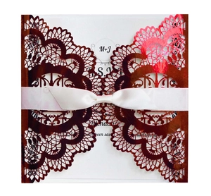 Elegant laser-cut floral wedding invitation in rose gold with white satin ribbon