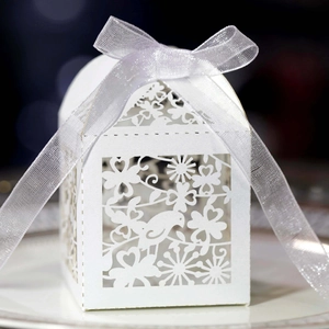 Detailed laser-cut pattern of birds and flowers on a white paper wedding favor gift box